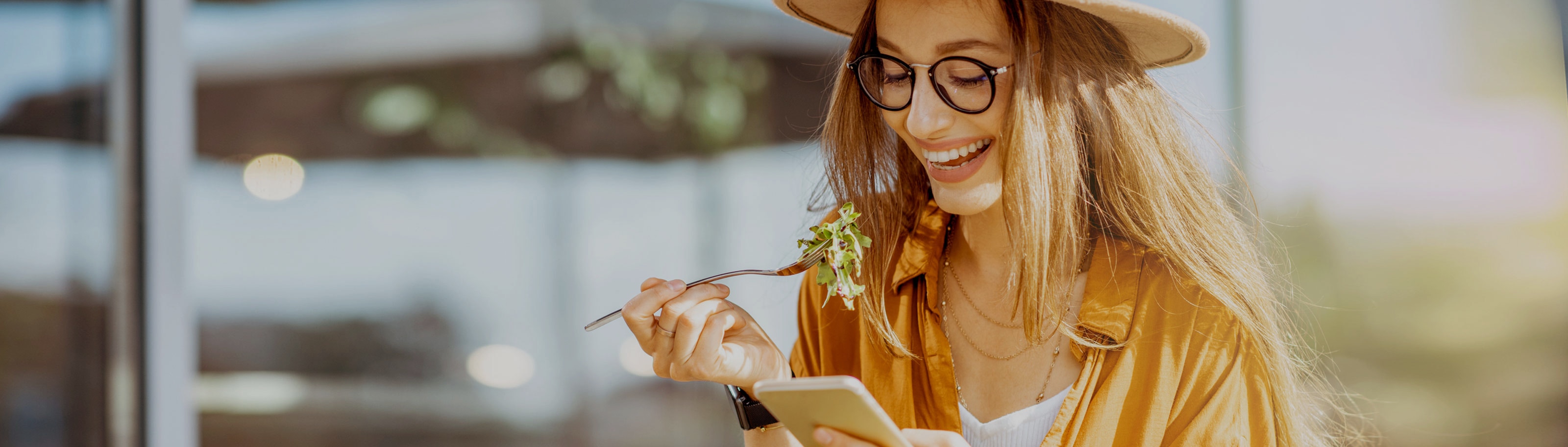 chica comiendo con un celular en un restaurante